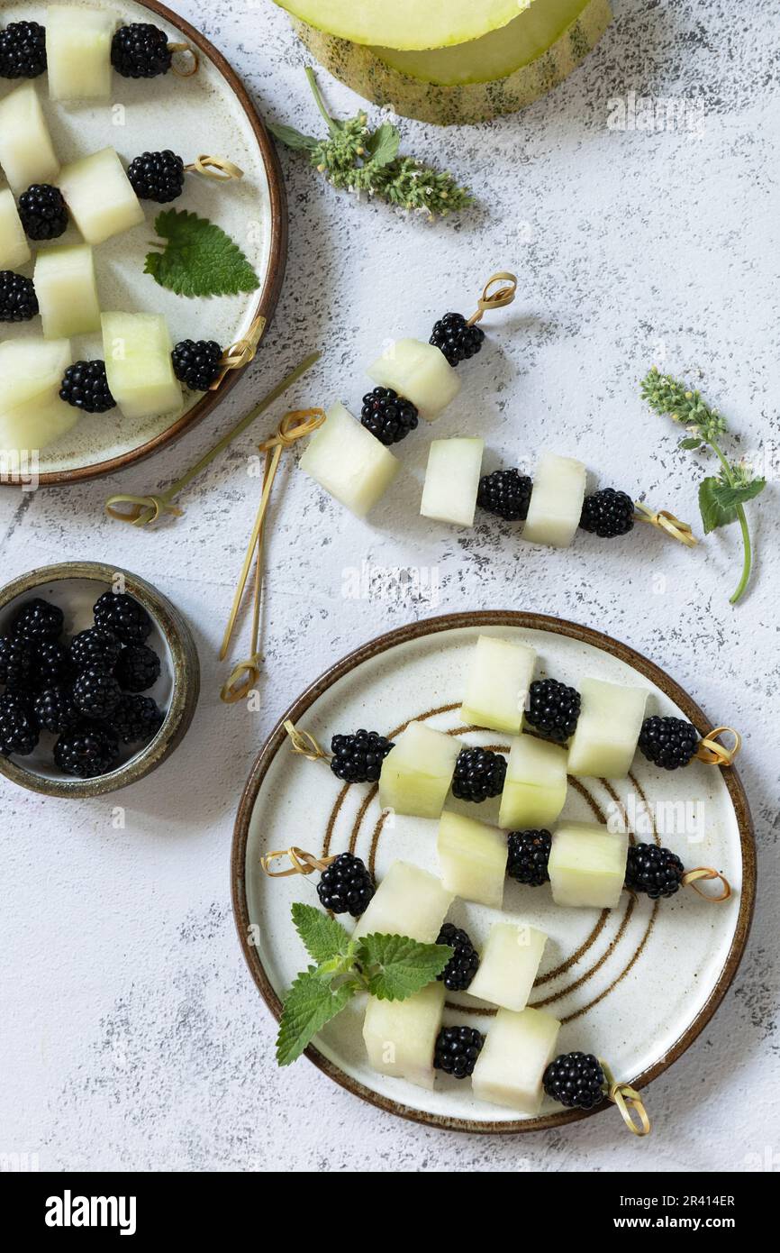 Festivo spuntino estivo di frutta e canape. Cibo vegano. Tartine con melone e more su un piano di pietra. Spazio di copia Foto Stock