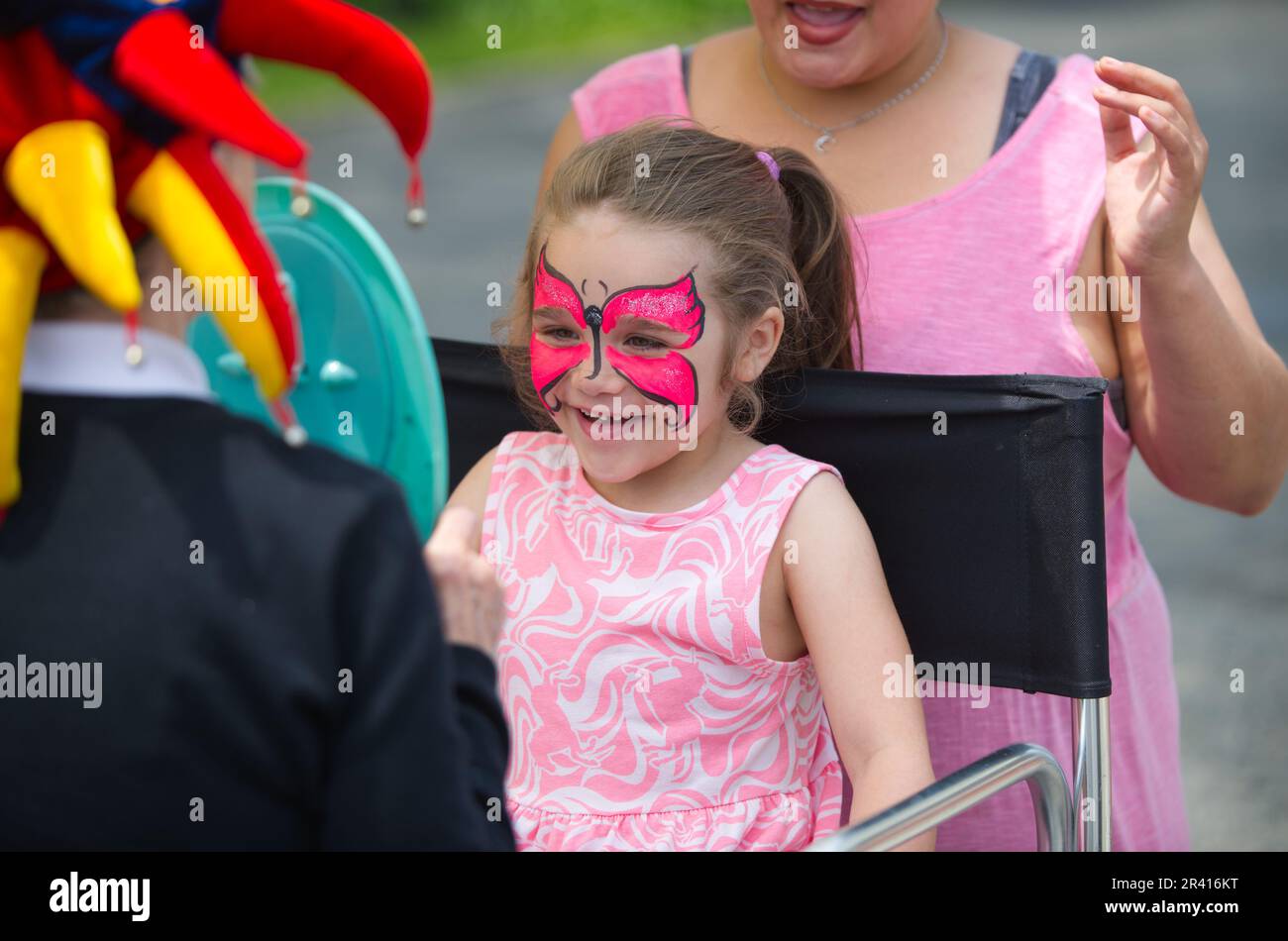 Open Streets - Hyannis, Massachusetts, USA. Una giovane ragazza esamina il suo quadro facciale in uno specchio. Foto Stock