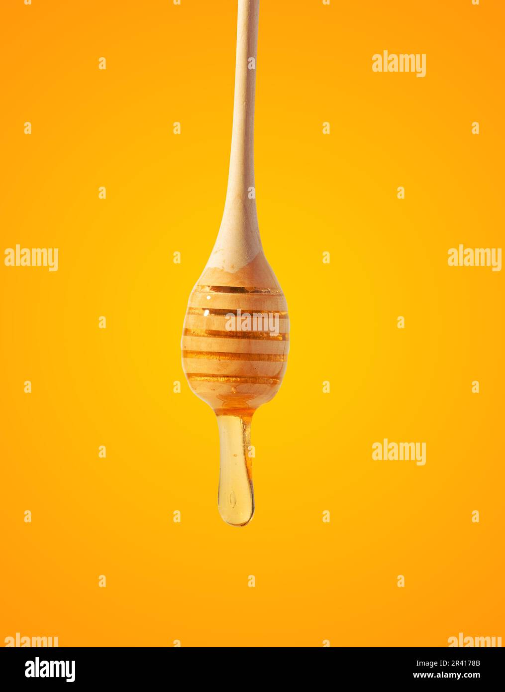 Gocce fluenti di miele giallo da un bastone di legno su uno sfondo giallo Foto Stock