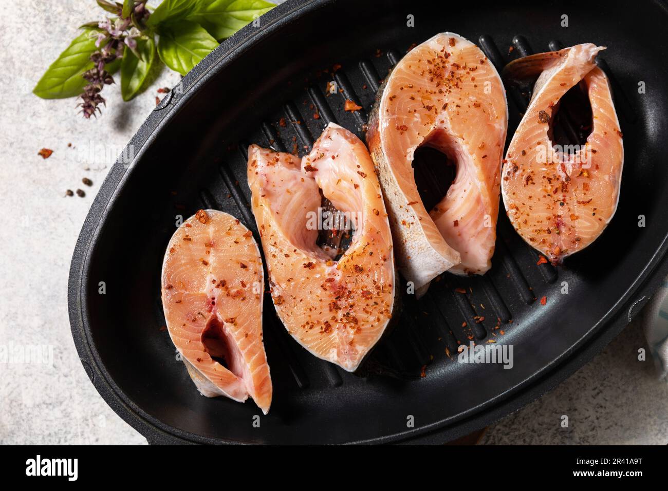 Pezzi di filetto di salmone fresco con spezie su una padella alla griglia. Pesce, sfondo culinario. Spazio di copia. Foto Stock