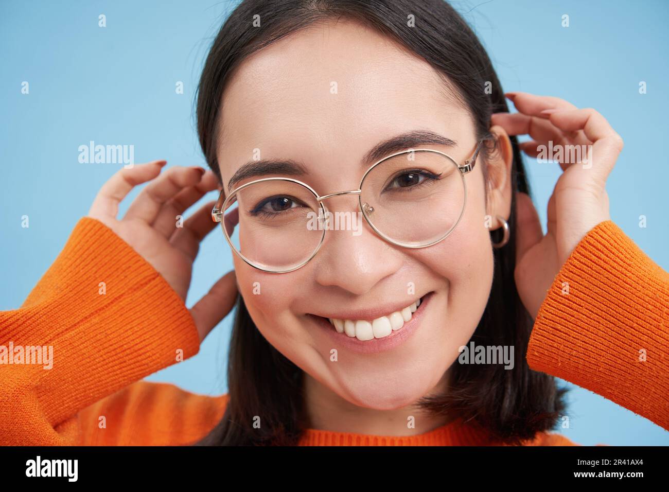 Primo piano ritratto di bella giovane donna asiatica in occhiali, sorridendo e guardando felice, cercando nuovi occhiali presso il negozio ottico, s Foto Stock