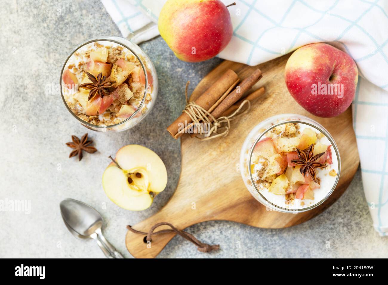 Dessert fatto in casa con yogurt, muesli, mele al caramello e cannella su un tavolo di pietra. Colazione sana granola, stile di vita sano Foto Stock