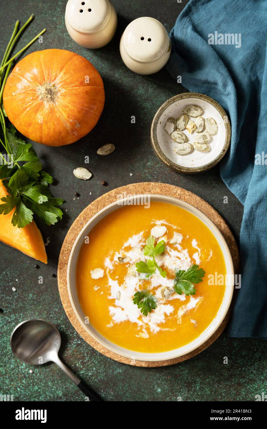 Zuppa vegetariana alla crema di zucca e carote con crema e semi di zucca su un tavolo di pietra. Comfort cibo, autunno e inverno sano Foto Stock