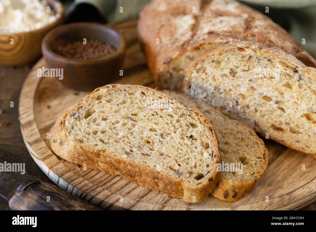 Pane di grani di grano intero, crusca di grano, semi, bioingredienti su sfondo rustico da tavola, stile di vita sano. Foto Stock