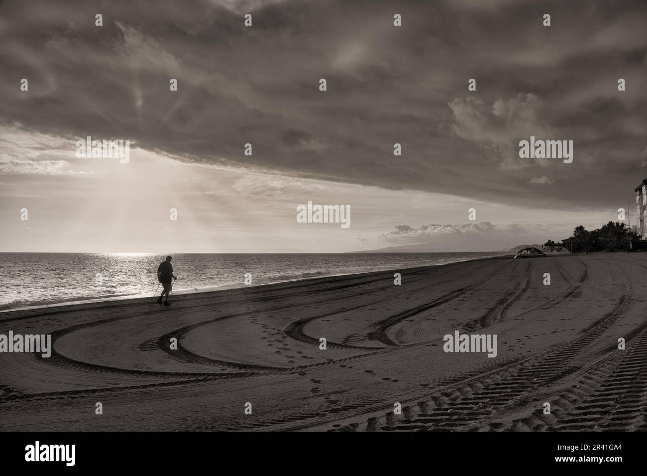 L'uomo cammina sulla spiaggia con bastoni da nordic walking Foto Stock