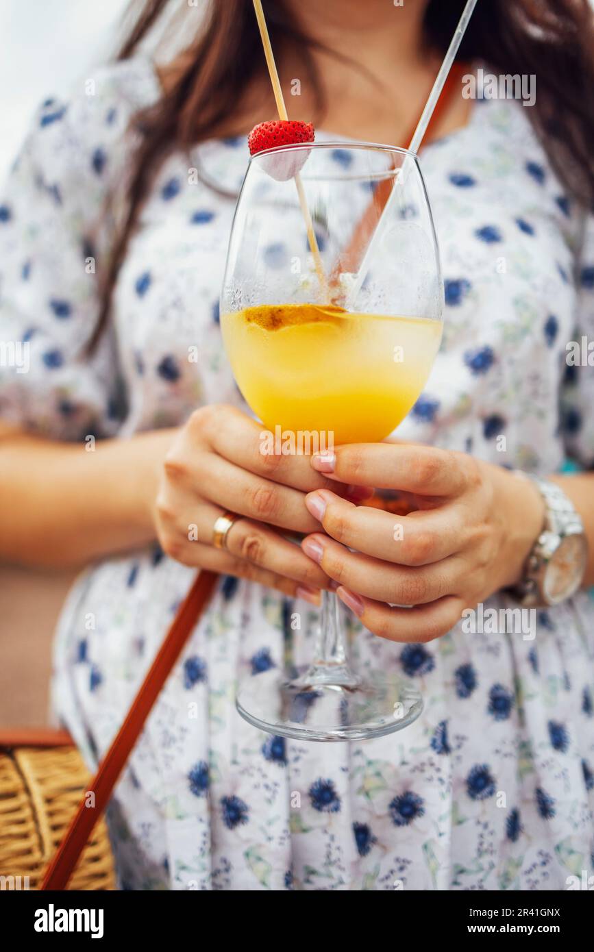 Primo piano delle mani femminili che tengono bicchieri di cocktail di acohol con frutta fresca e frutti di bosco Foto Stock