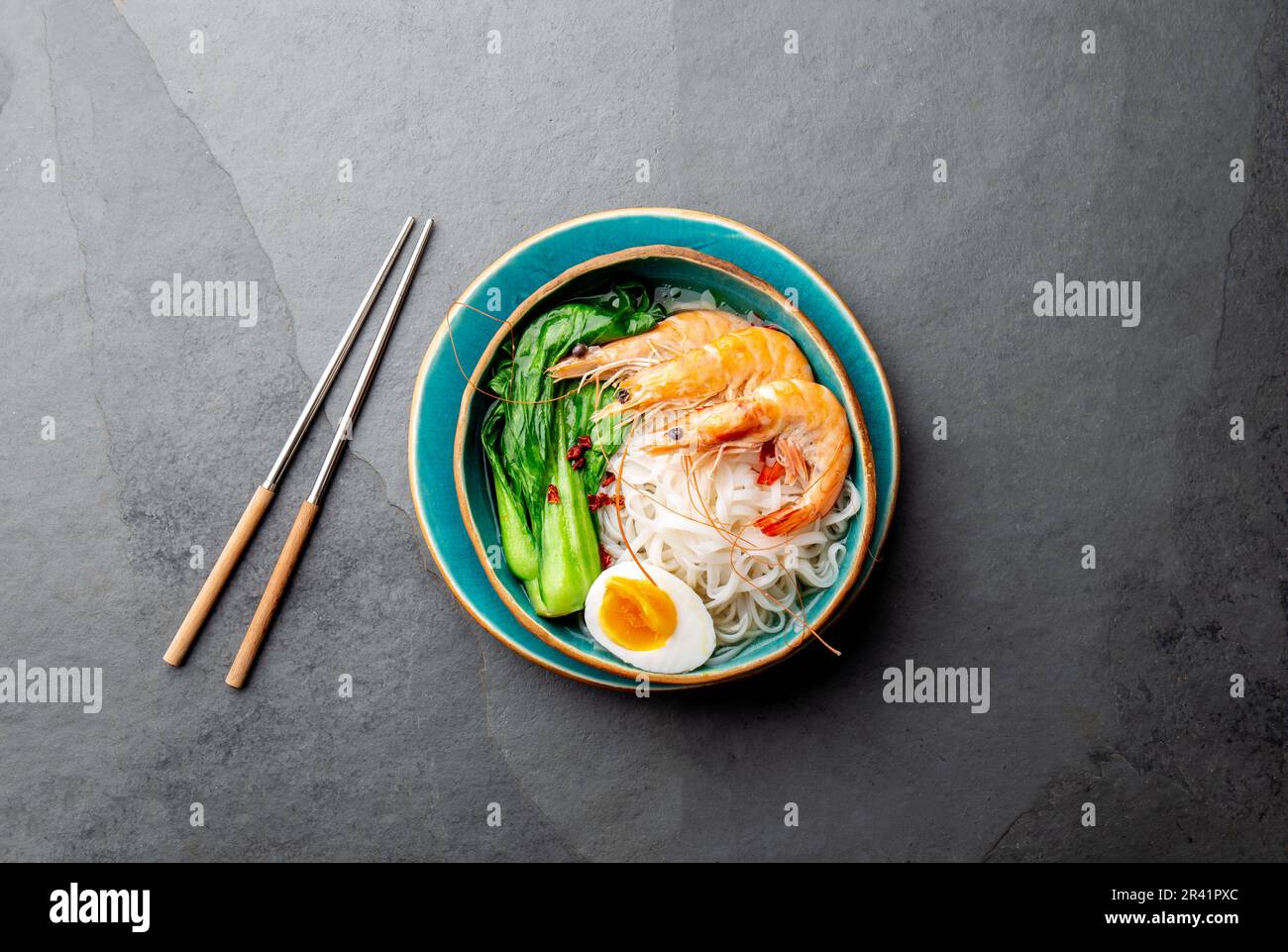 Tagliatelle asiatiche di riso con gamberetti su fondo grigio Foto Stock