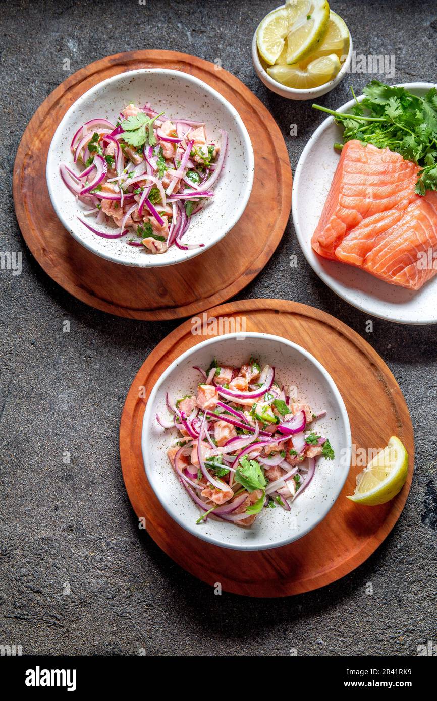 SALMONE CILENO SEVICHE. Salmone crudo fresco marinata con cipolla viola, coriandolo in succo di limone. Ceviche e ingredienti sul grigio Foto Stock