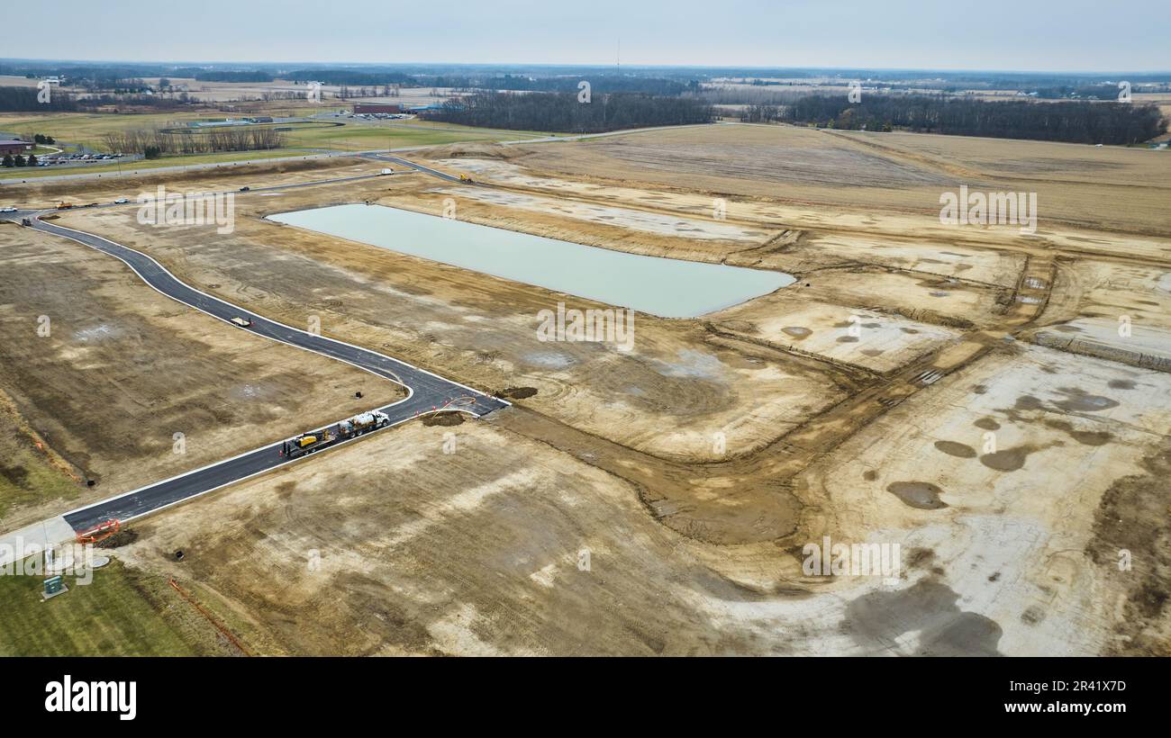 Drone ripresa aerea di quartiere suburbano costruzione di alloggi in Midwest America con grande stagno strada asfaltata e sterrato Foto Stock