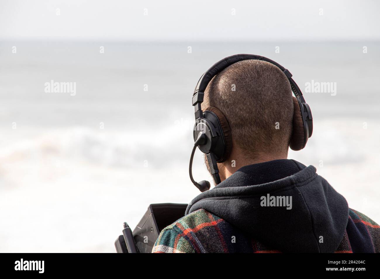 Cameraman con cuffie che girano alla spiaggia Foto Stock