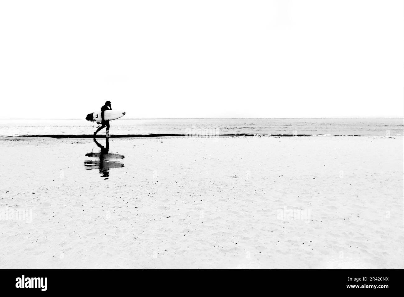 Surfista e riflessioni su una spiaggia minimalista Foto Stock