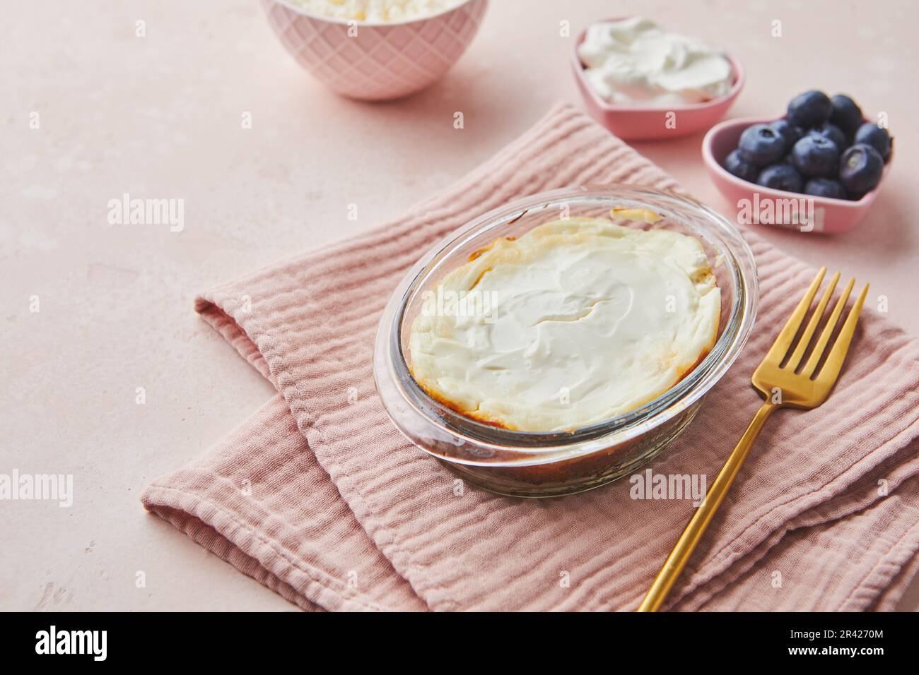 Deliziosa casseruola di formaggio casolare in vetro porzionato con panna acida. Cucina tradizionale russa per colazione - Zapekan Foto Stock