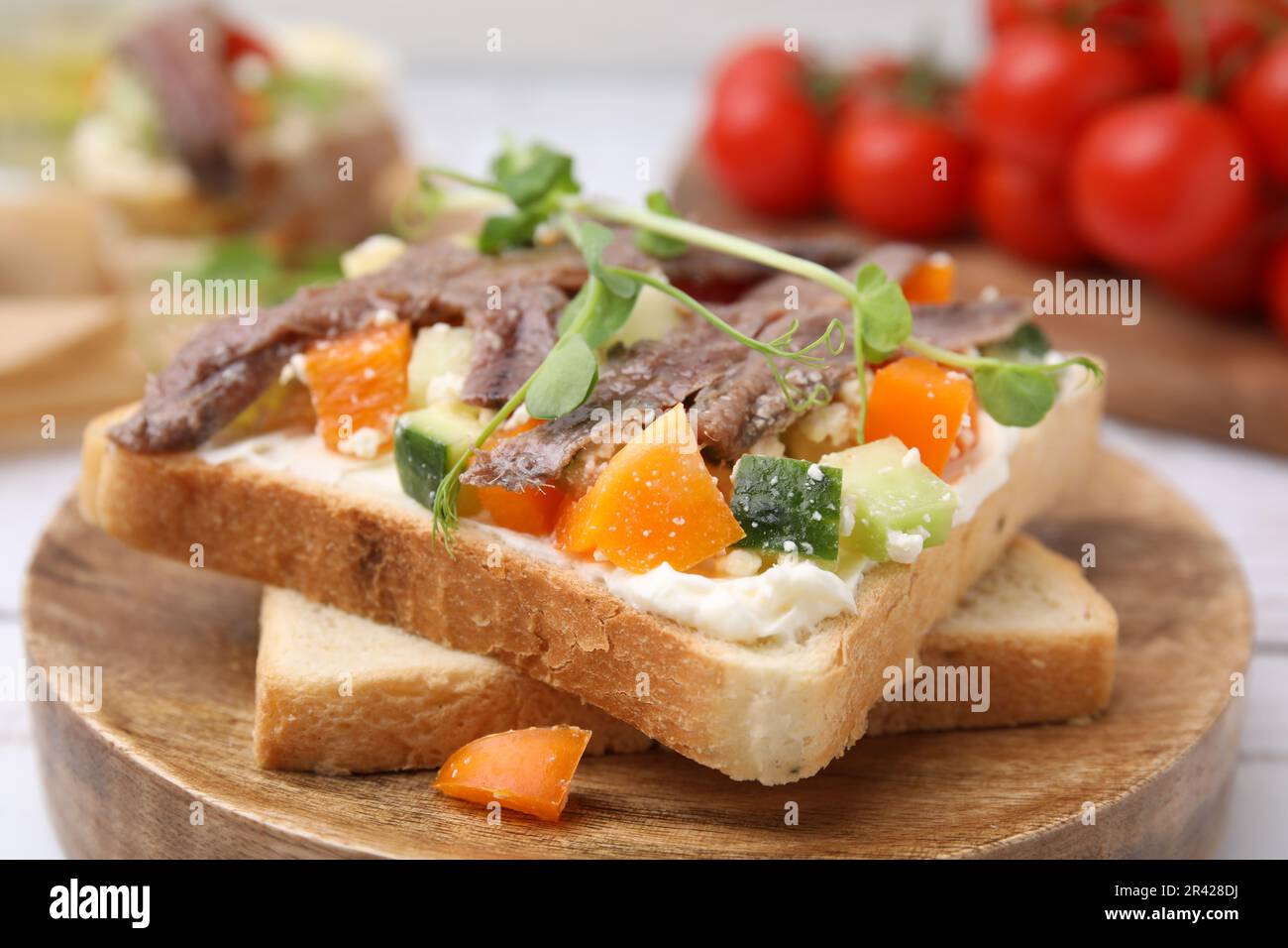 Toast deliziosi con acciughe, formaggio cremoso, peperoni e cetrioli su tavola bianca, primo piano Foto Stock