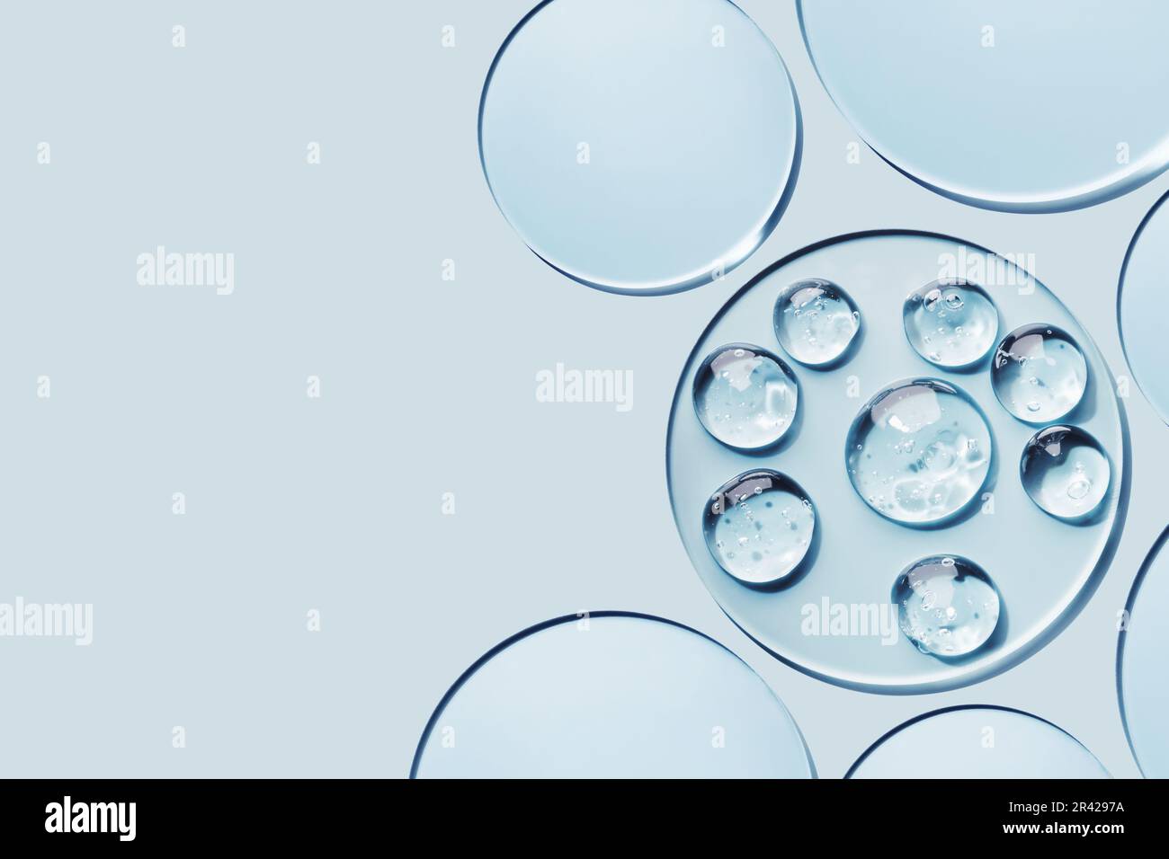 Campioni di prodotti cosmetici in gel in una capsula di Petri su sfondo blu, ombre dure Foto Stock