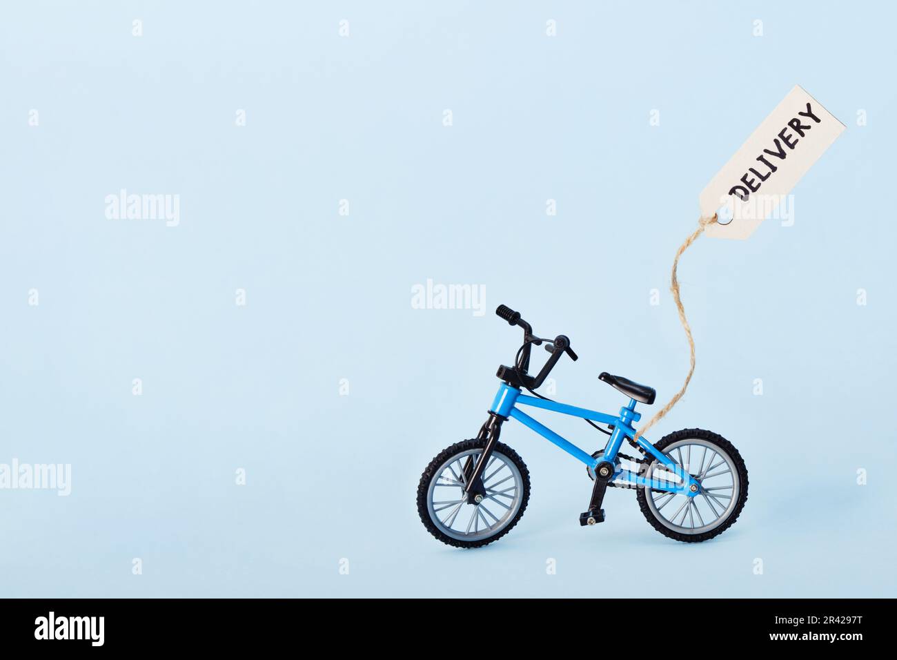 Concetto creativo di eco-consegna. Bicicletta ed etichetta con testo di consegna su sfondo blu Foto Stock