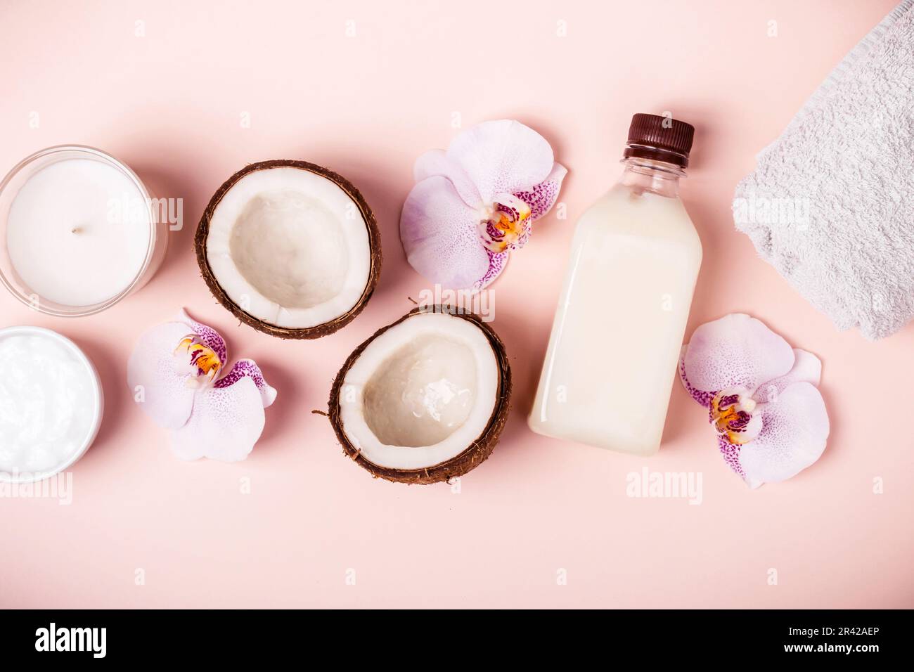 Olio di cocco e metà di cocco fresco su sfondo rosa. Concetto spa per la cura dei capelli Foto Stock