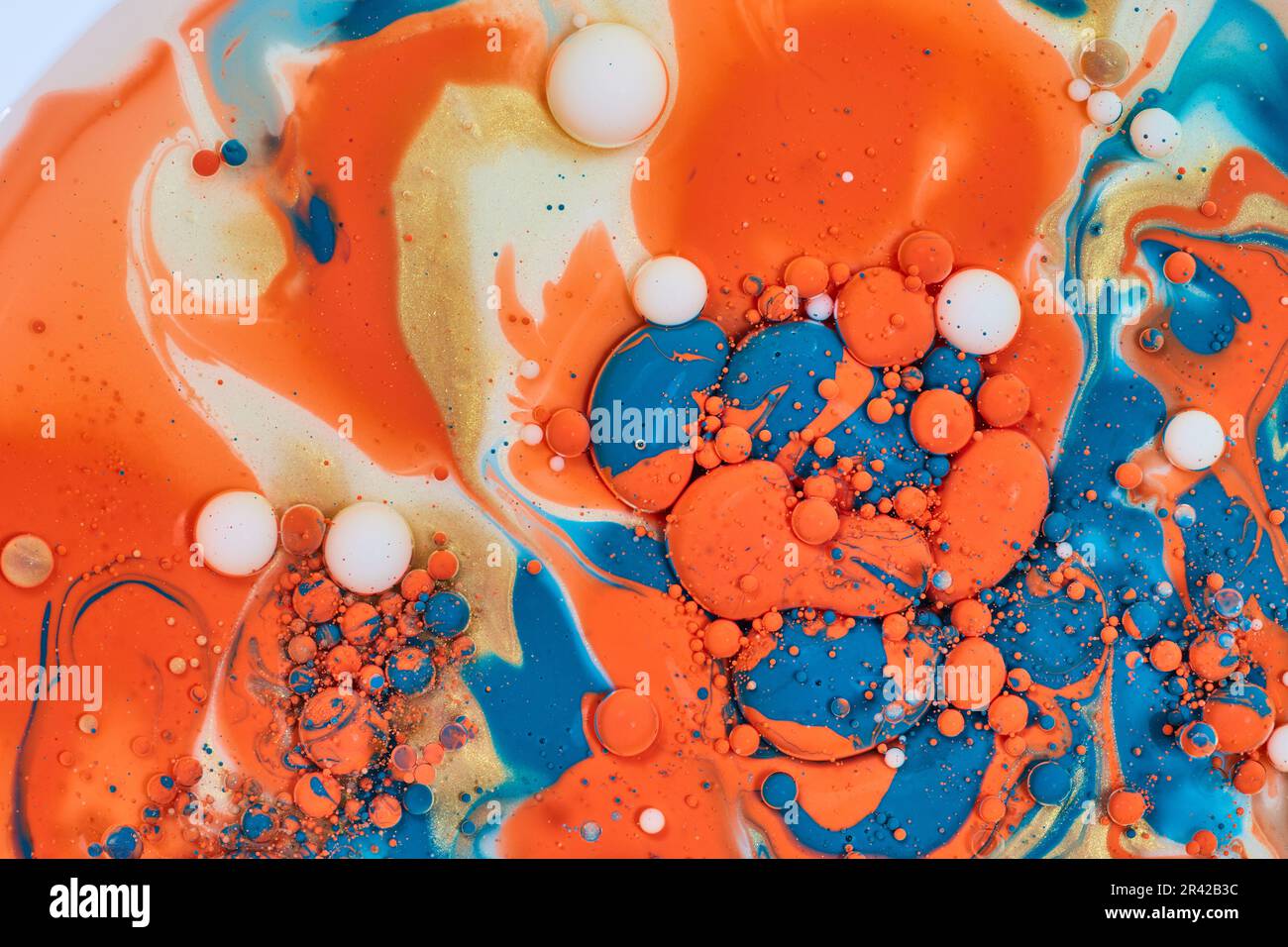 Ballo astratto orizzontale di goccia di olio di crema dorata mescolando con vernice acrilica arancione e blu in risorsa di fondo Foto Stock