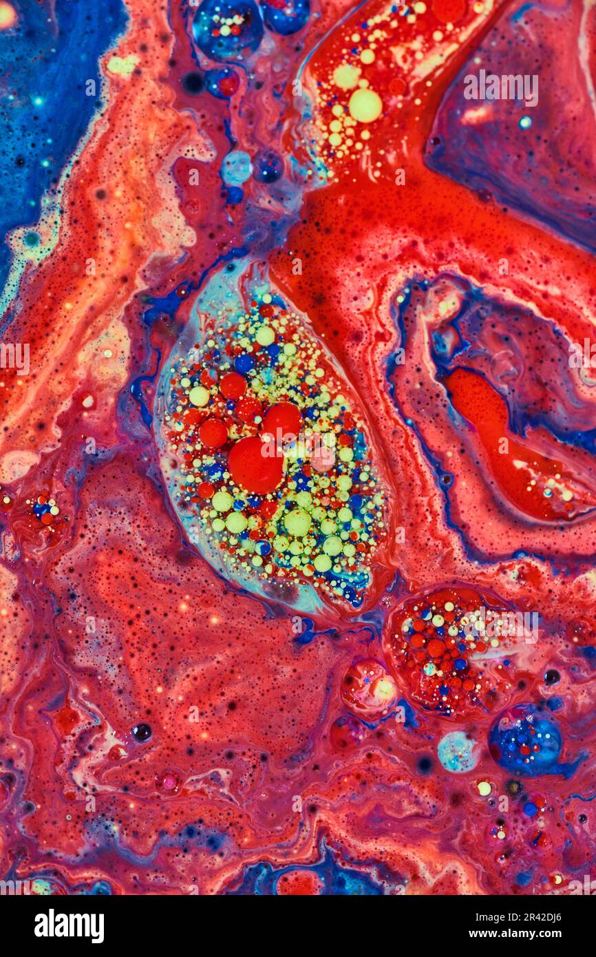 Embrione astratto di bolle acriliche rosse e gialle circondato da un mare di vernice rossa in risorsa di fondo Foto Stock