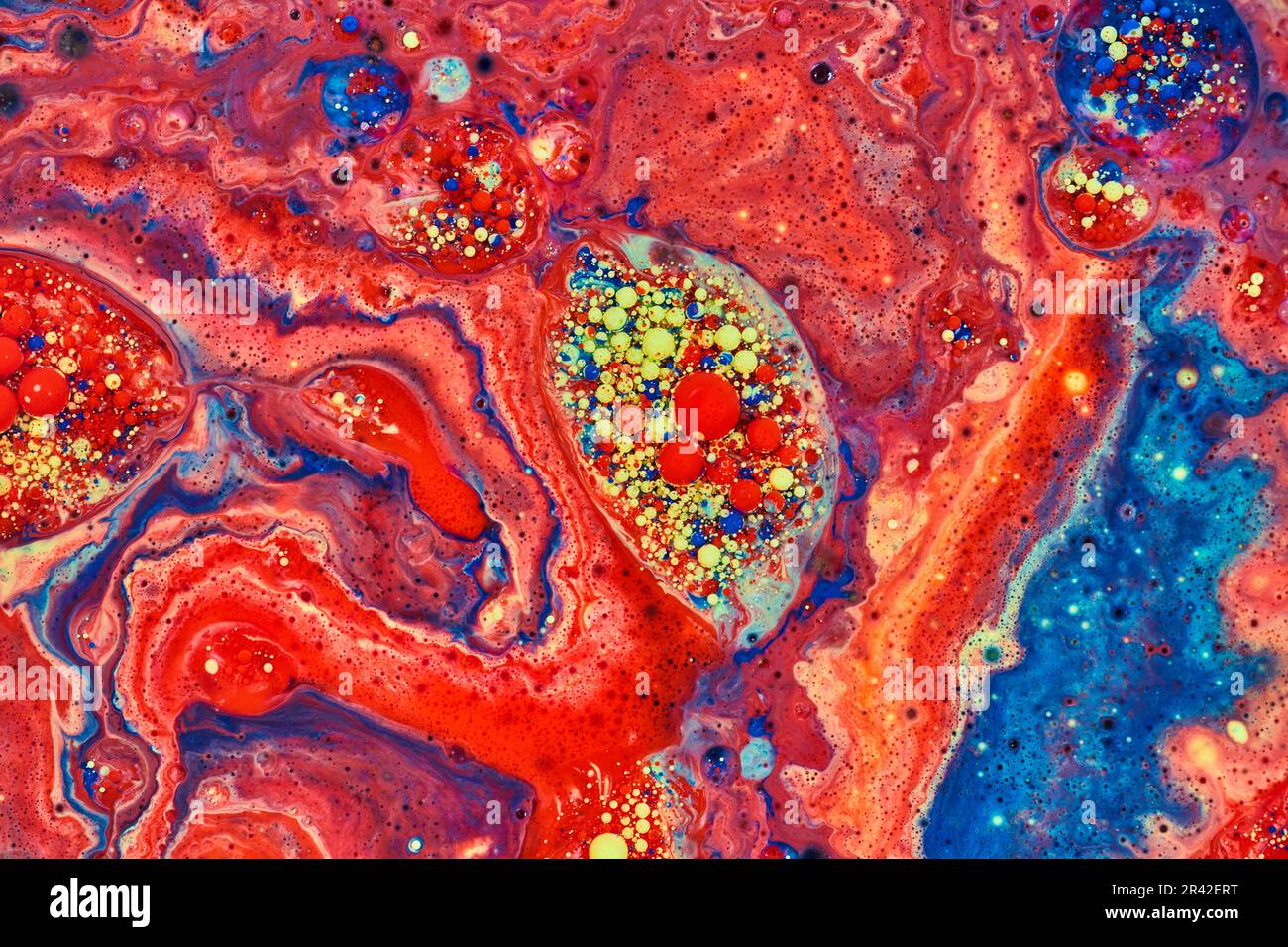 Embrione astratto orizzontale di bolle acriliche rosse e gialle circondato da un mare di vernice rossa in risorsa di fondo Foto Stock