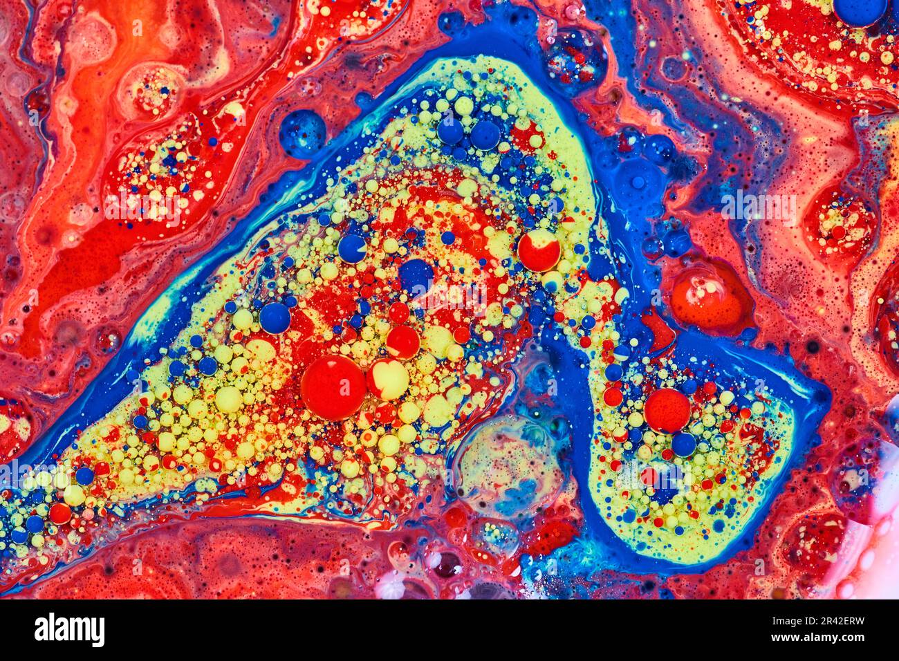 Pittura acrilica blu rossa e gialla con bolle d'olio e di latte e sfere in fondo galattico astratto Foto Stock