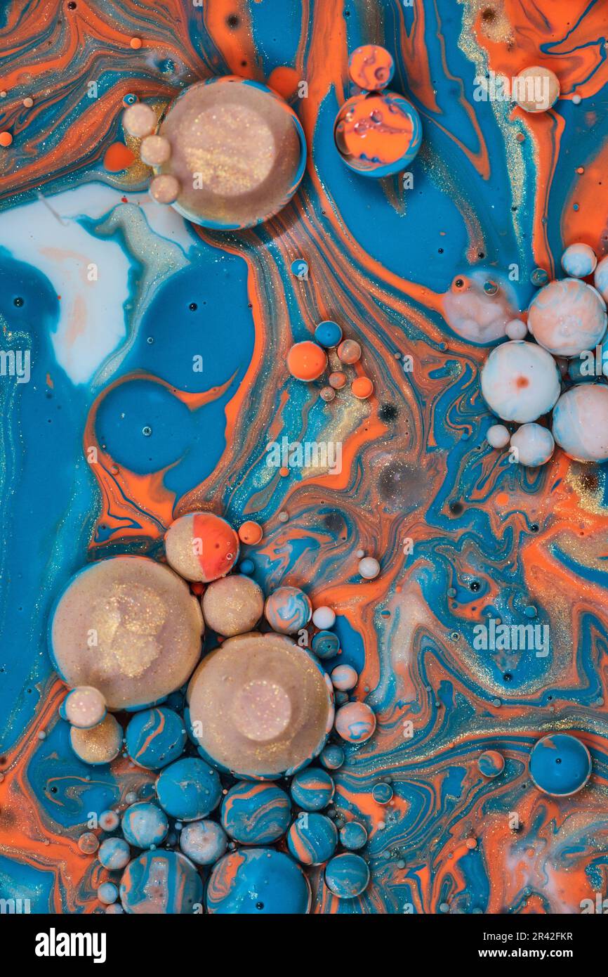 Colpo verticale di bolle galleggianti di oro arancione blu e bianco vernice in risorsa astratta sfondo Foto Stock