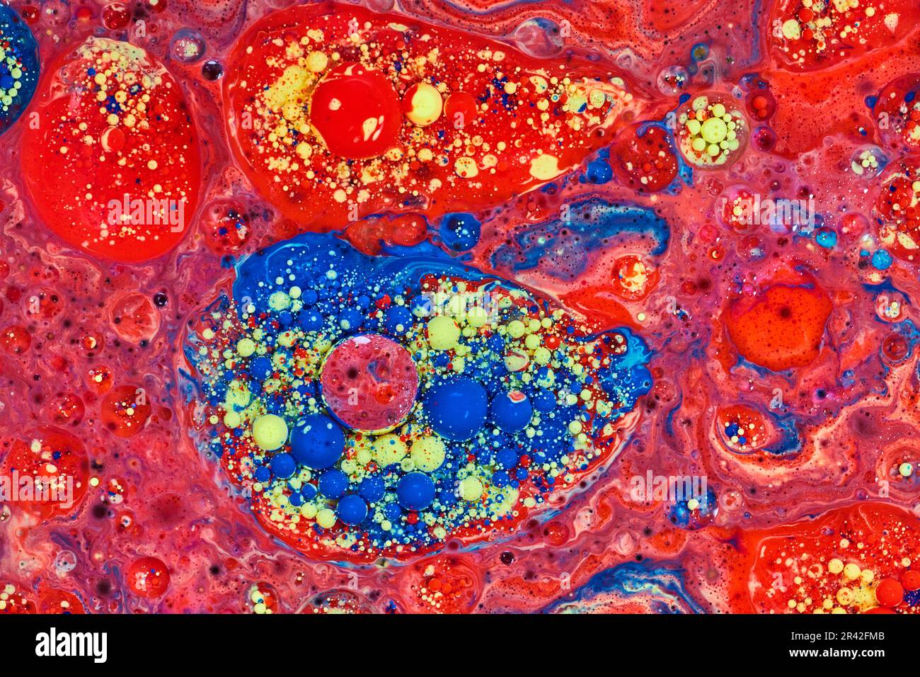Isola astratta di bolle blu gialle e rosse in pittura acrilica con un mare di stelle rosse in cosmo come risorsa di fondo Foto Stock
