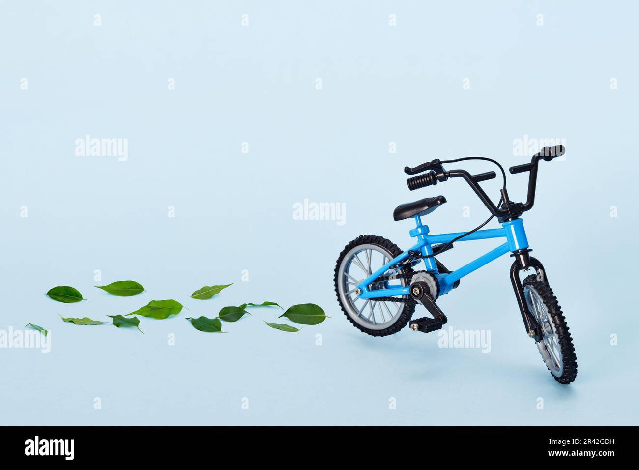 Giornata mondiale della bicicletta. Bicicletta che emette foglie verdi fresche su sfondo blu. Concetto sostenibile e sano Foto Stock