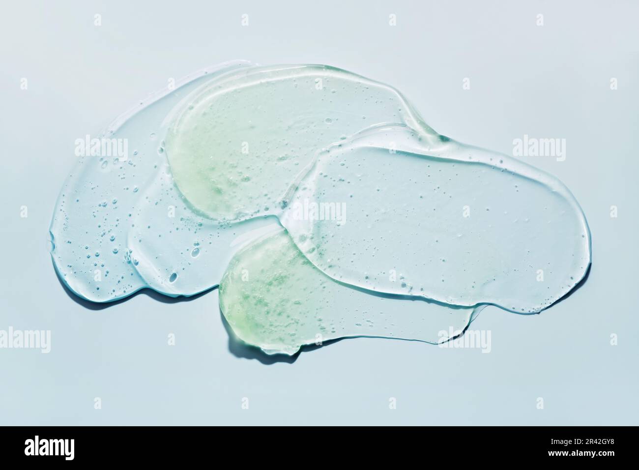 Strisci di gel cosmetico astratto liquido su sfondo blu. Striscio di prodotto idratante trasparente Foto Stock