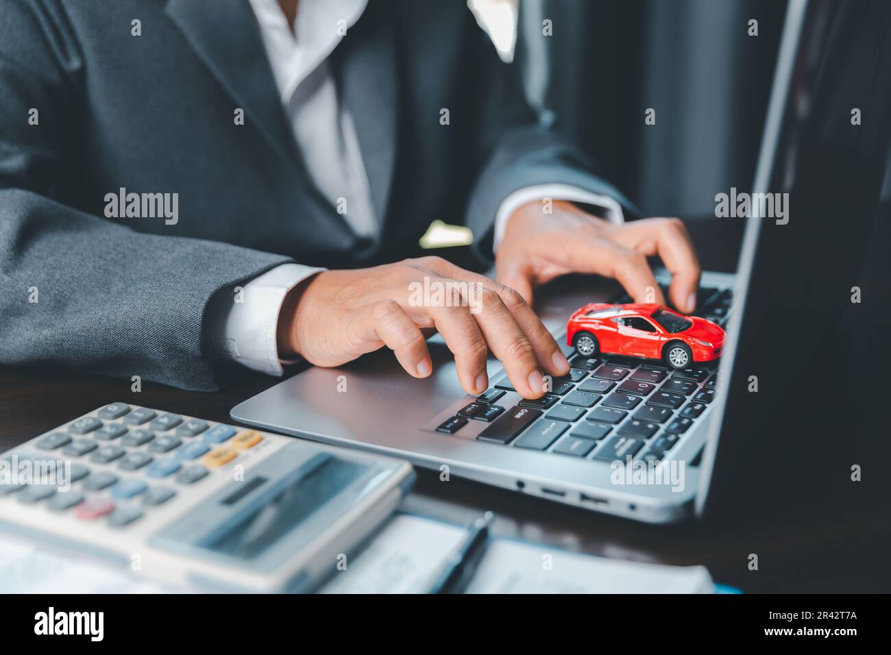 Primo piano di una piccola auto rossa sulla tastiera del computer portatile.  Pianificazione della gestione dei costi di finanziamento dei trasporti.  Concetto di assicurazione auto business, risparmio di acquistare con le  tasse