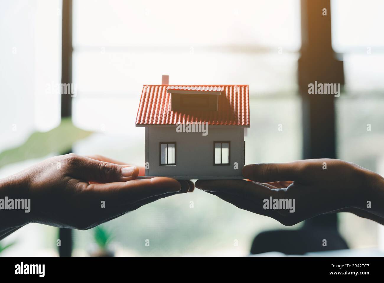 Donna d'affari che tiene in casa miniatura in ufficio ufficio ufficio. Assicurazione protezione della mano sopra la casa per la protezione e la cura, concetto della casa e del bene immobile Foto Stock