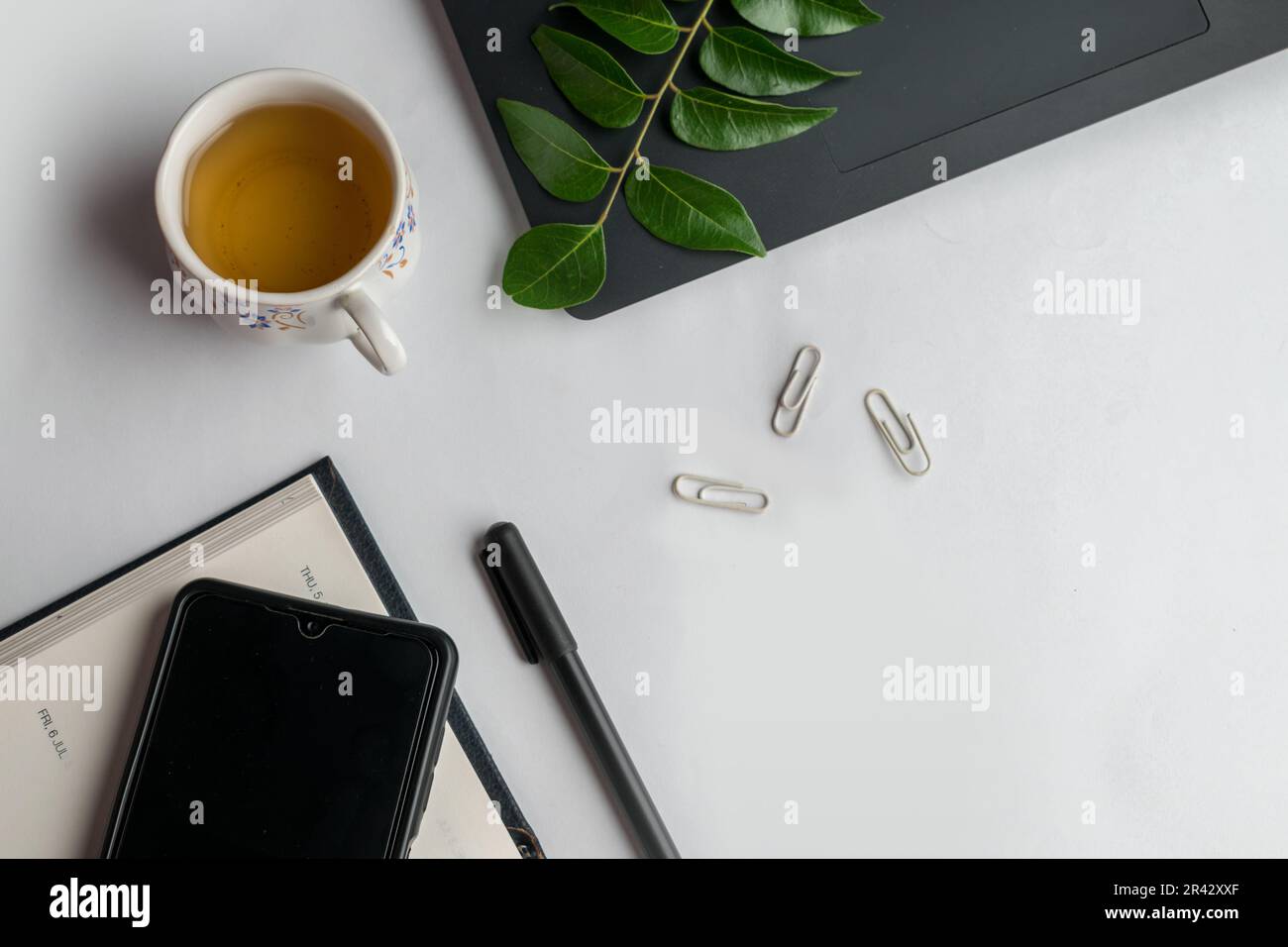 Design piatto della scrivania con notebook, penna, computer portatile, cellulare e graffette su sfondo bianco. Foto Stock Design piatto della scrivania con notebook, penna, computer portatile, cellulare e graffette su sfondo bianco. Foto Stock