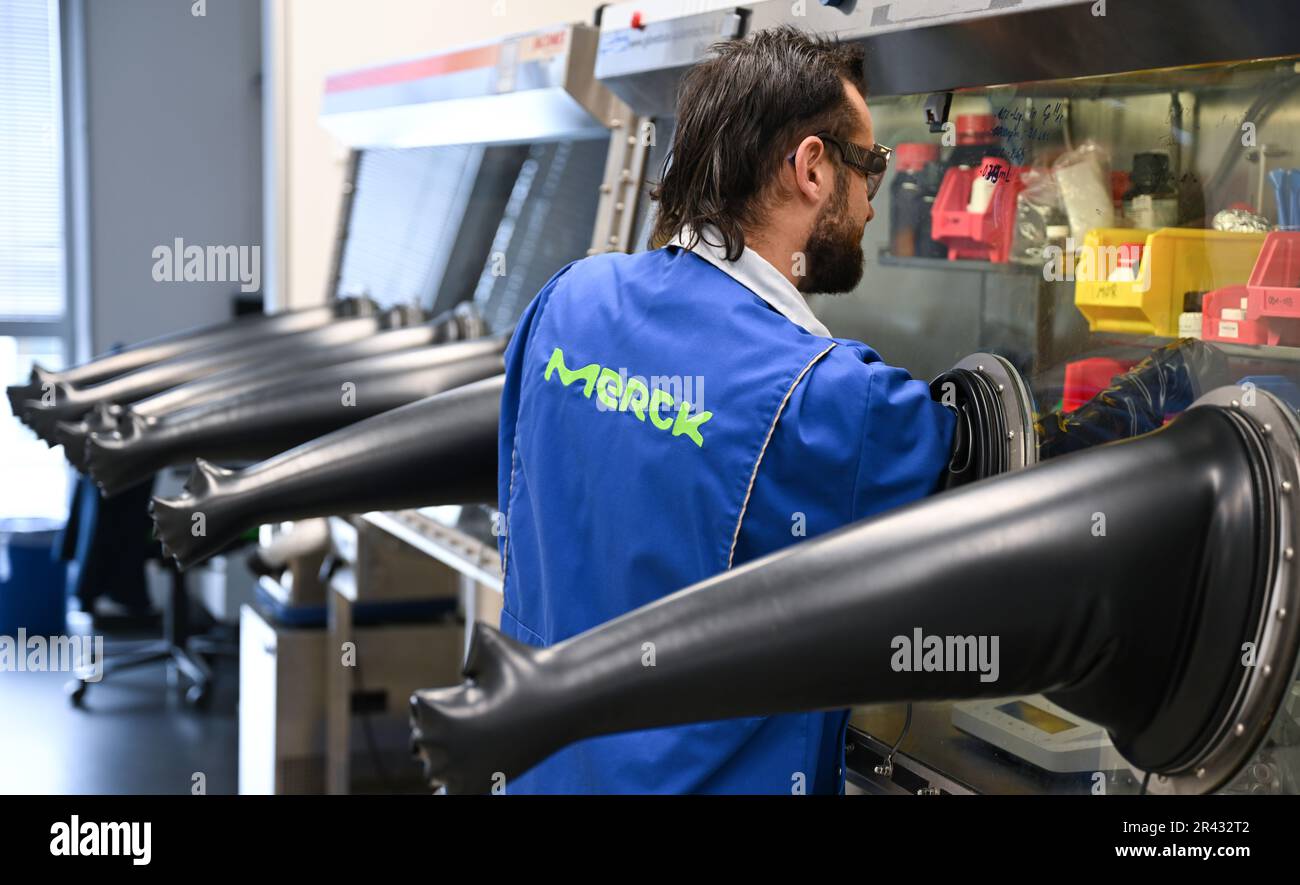 Darmstadt, Germania. 23rd maggio, 2023. Paul Mehlmann, scienziato nel settore dell'elettronica del gruppo farmaceutico e tecnologico Merck KGaA, con sede a Darmstadt, lavora in un cosiddetto 'cassetto portaoggetti' con molecole utilizzate per la produzione di semiconduttori. Questi materiali sono estremamente sensibili e si decompongono al contatto con ossigeno e umidità. Credit: Arne Dedert/dpa/Alamy Live News Foto Stock