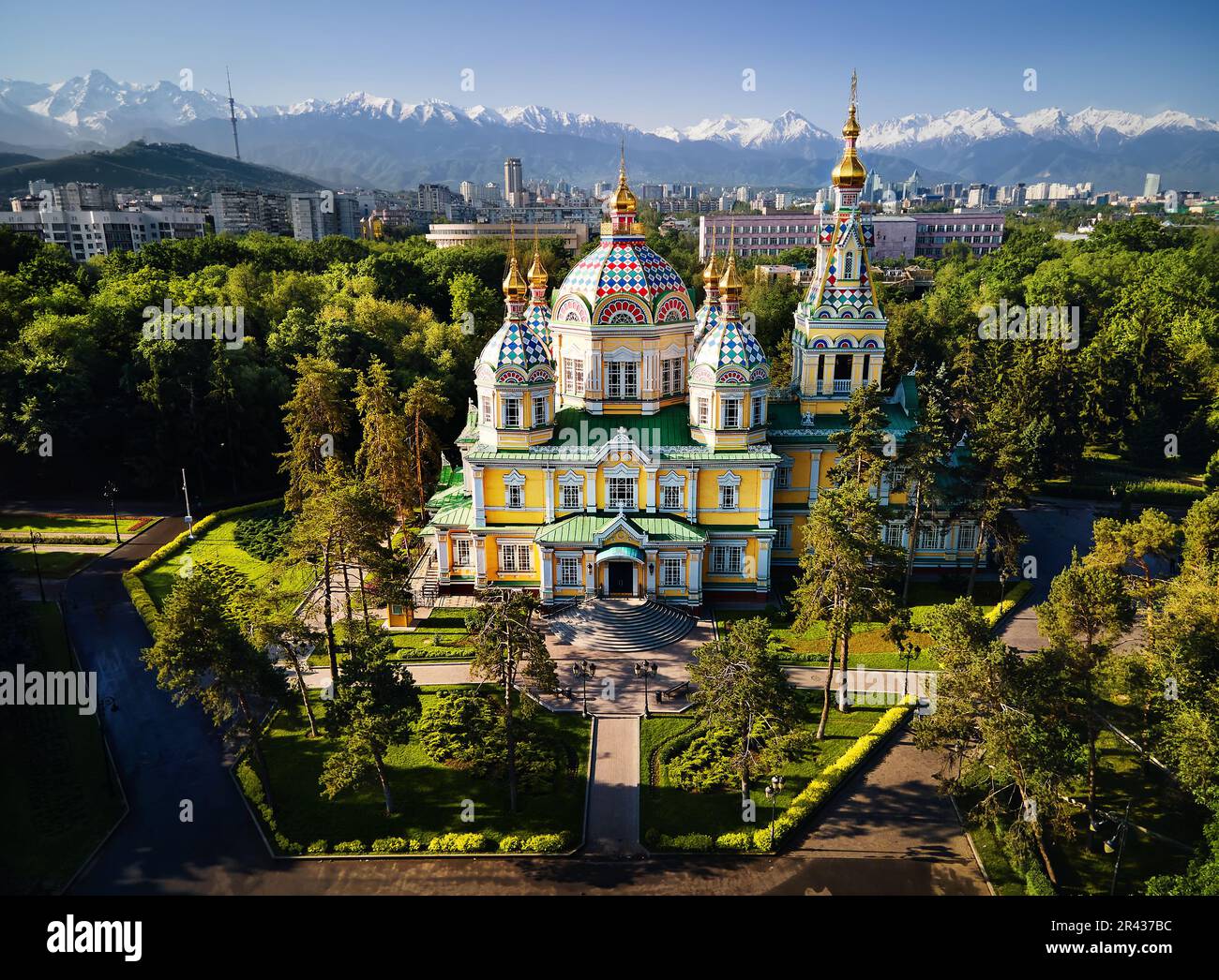 Panorama aereo del drone della Cattedrale dell'Ascensione Chiesa ortodossa russa e montagne di neve sullo sfondo nel Parco Panfilov contro il cielo blu in Almaty Foto Stock