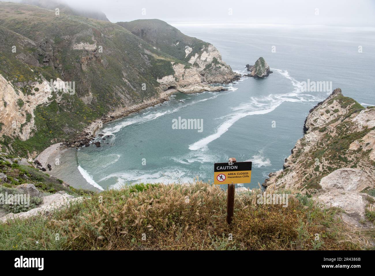 Un cartello che avverte i visitatori che ci sono scogliere pericolose e cascate pericolose al porto di Potato si affaccia sul Channel Islands National Park, California. Foto Stock