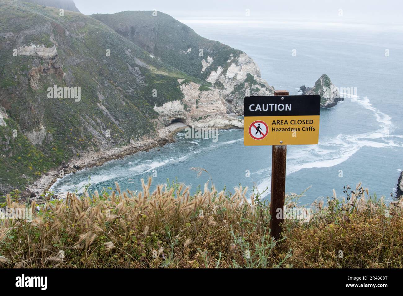 Un cartello che avverte i visitatori che ci sono scogliere pericolose e cascate pericolose al porto di Potato si affaccia sul Channel Islands National Park, California. Foto Stock