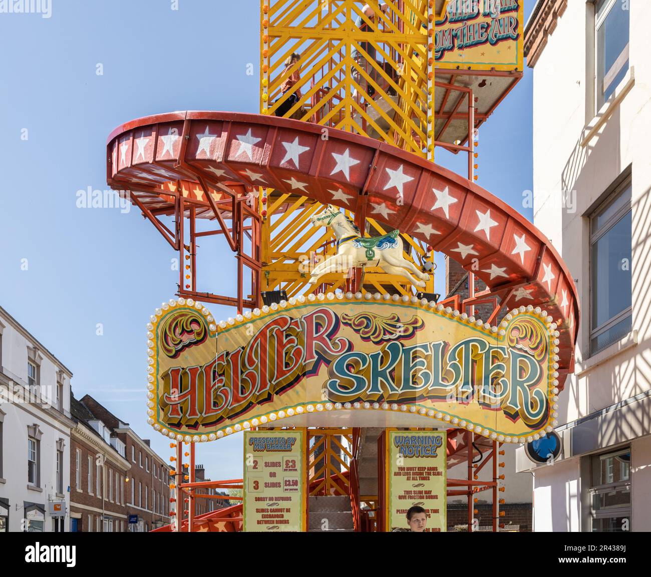 Un tradizionale giro in Helter Skelter, con colori vivaci e una meravigliosa segnaletica che si erge in un ambiente urbano. Foto Stock