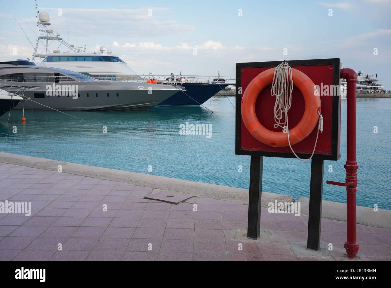 Salvagente rosso in una baia blu dell'oceano con uno yacht di lusso sullo sfondo Foto Stock