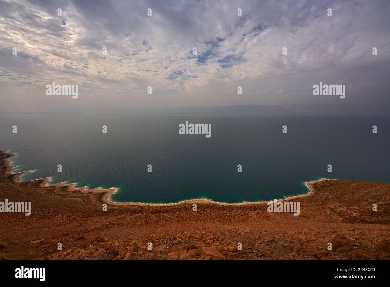 Mar Morto, paesaggio dalla vista della Giordania. Costa, acqua con cielo blu con nuvole. Lago salato confinante con la Giordania a est e la Cisgiordania e Israele t Foto Stock