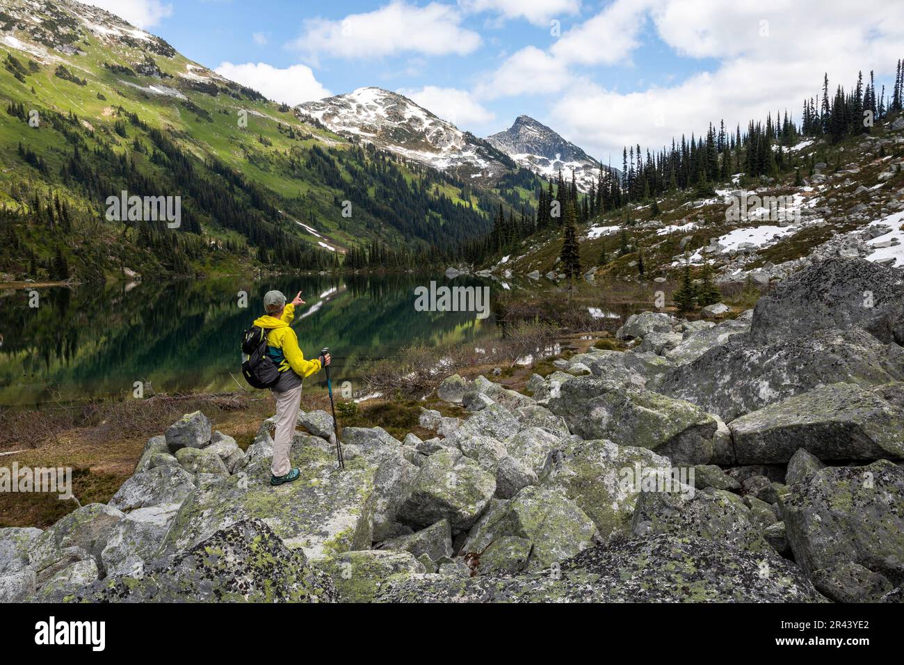 Vista posteriore dell'escursionista con zaino rivolto verso le montagne e un lago Foto Stock