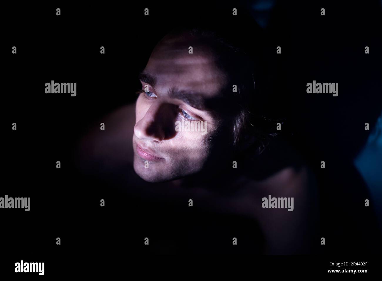Ritratto di un uomo in una stanza buia, illuminato da un raggio di luce Foto Stock
