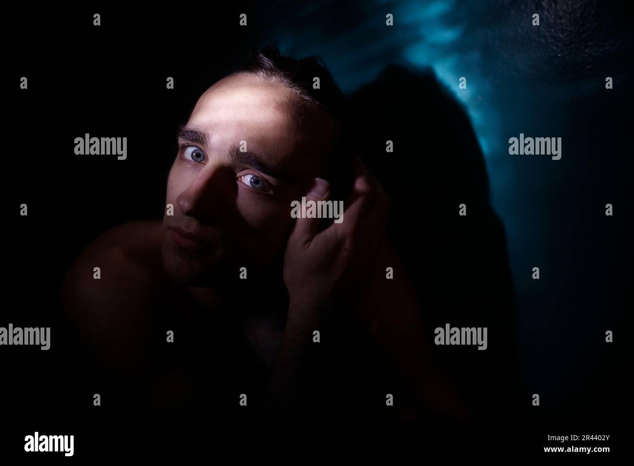 Ritratto di un uomo in una stanza buia, illuminato da un raggio di luce Foto Stock