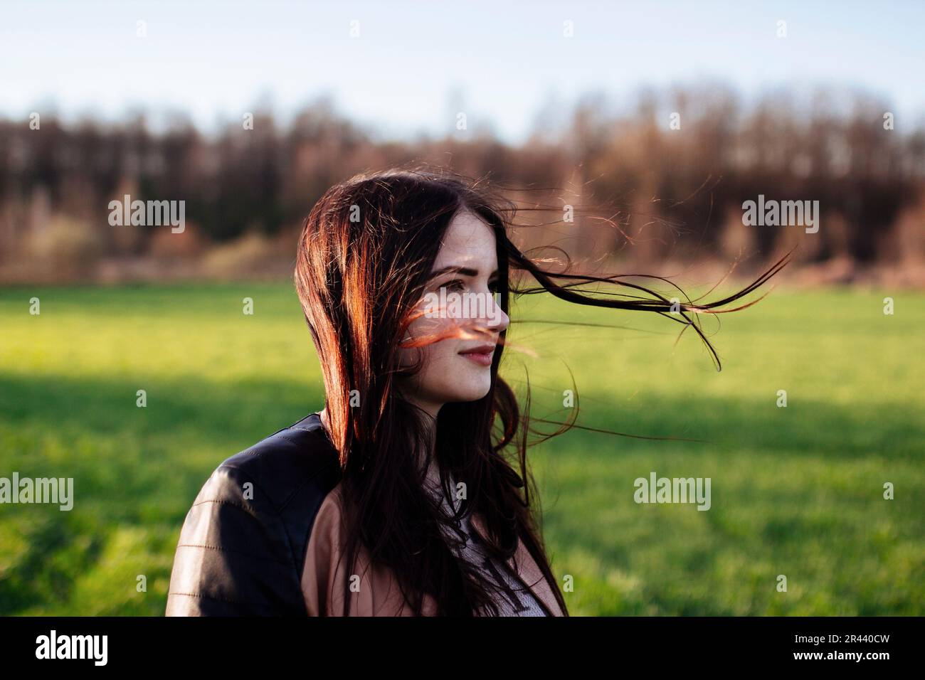 donna in piedi nel campo i capelli si sviluppa nel vento Foto Stock