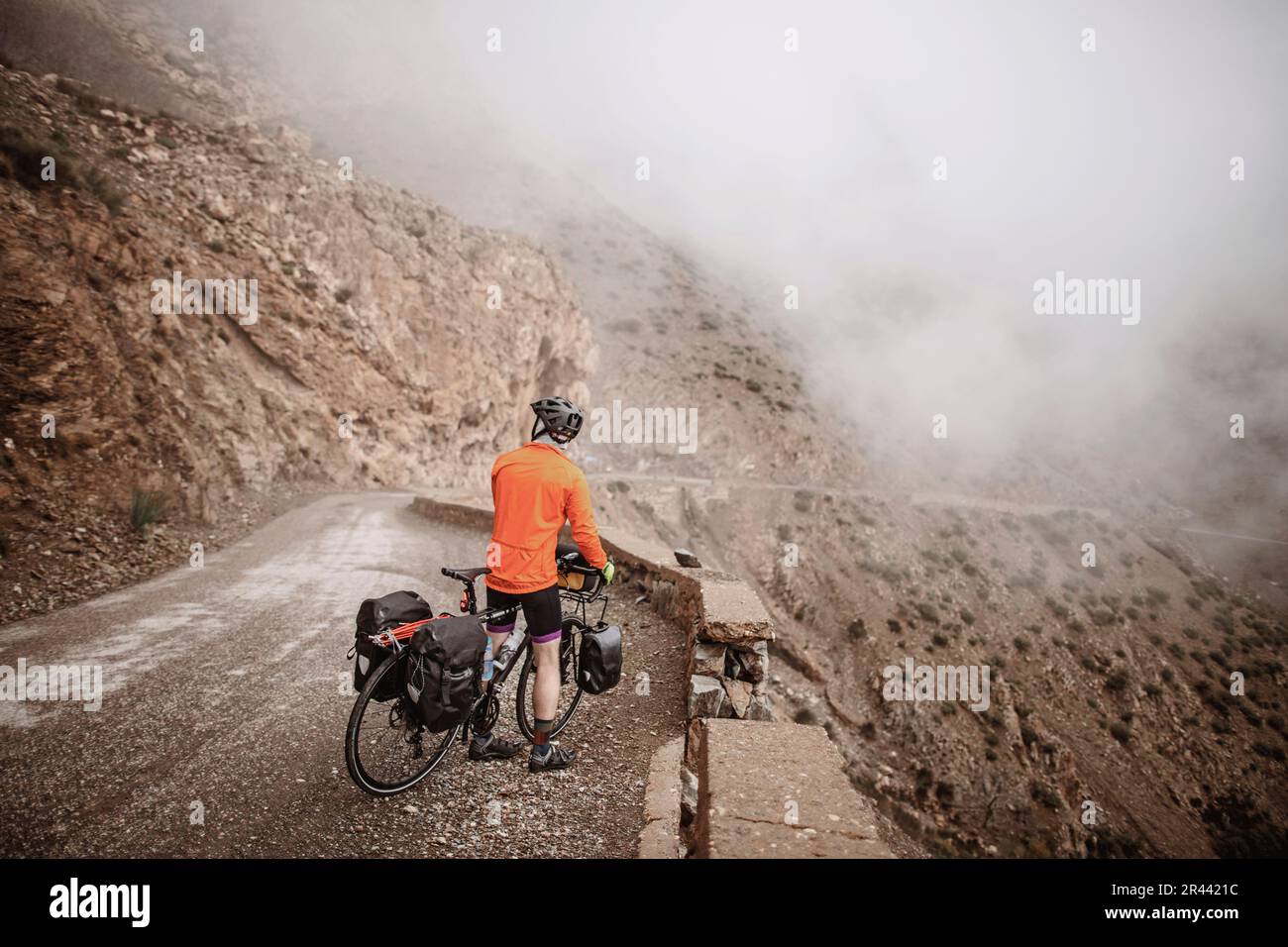 Un ciclista make guarda la vista nuvolosa dal Tizi n Test Pass, Marocco Foto Stock