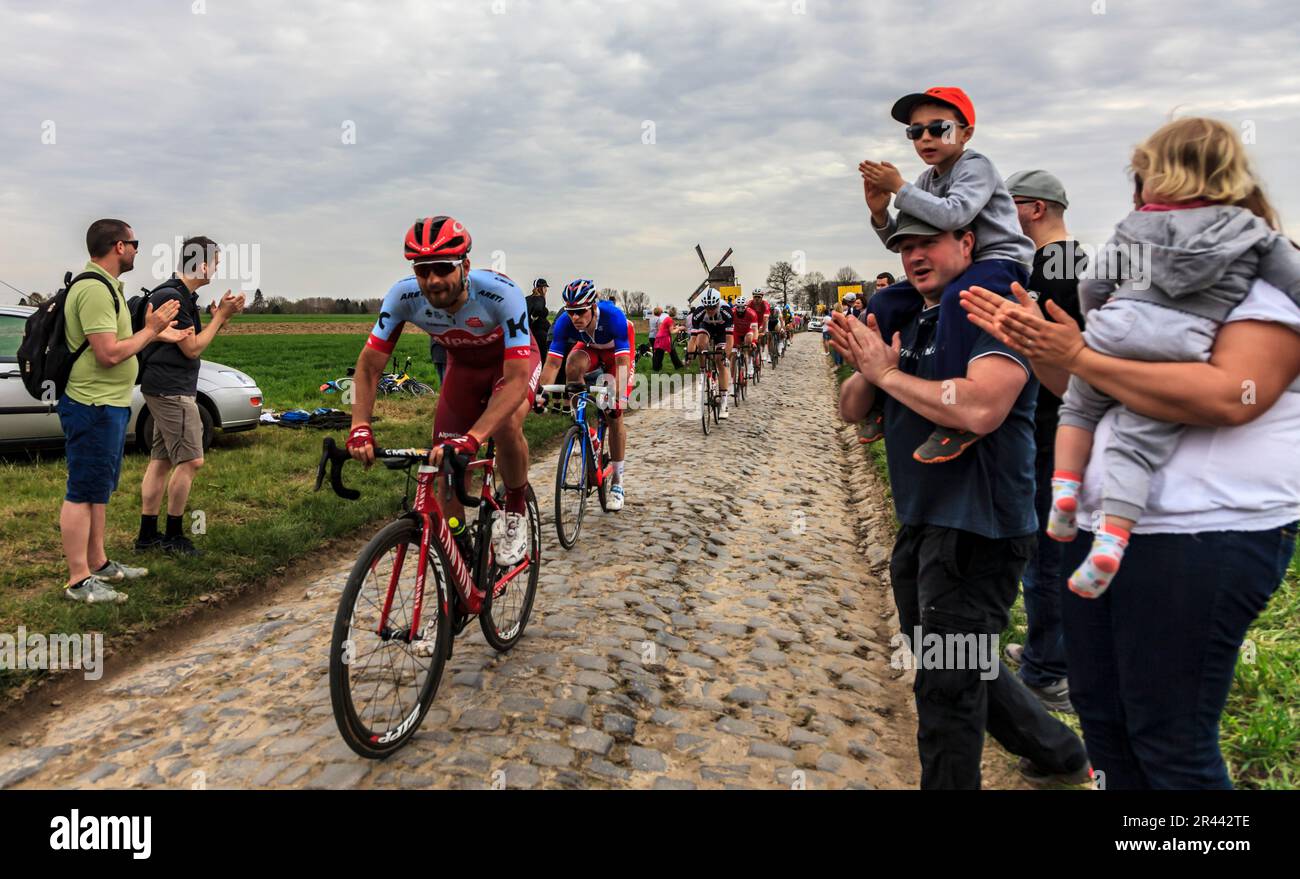 Templeuve, Francia - Aprile 08, 2018: il peloton cavalcare sulla strada acciottolata in Templeuve davanti alla tradizionale mulino a vento Vertain durante Paris- Foto Stock