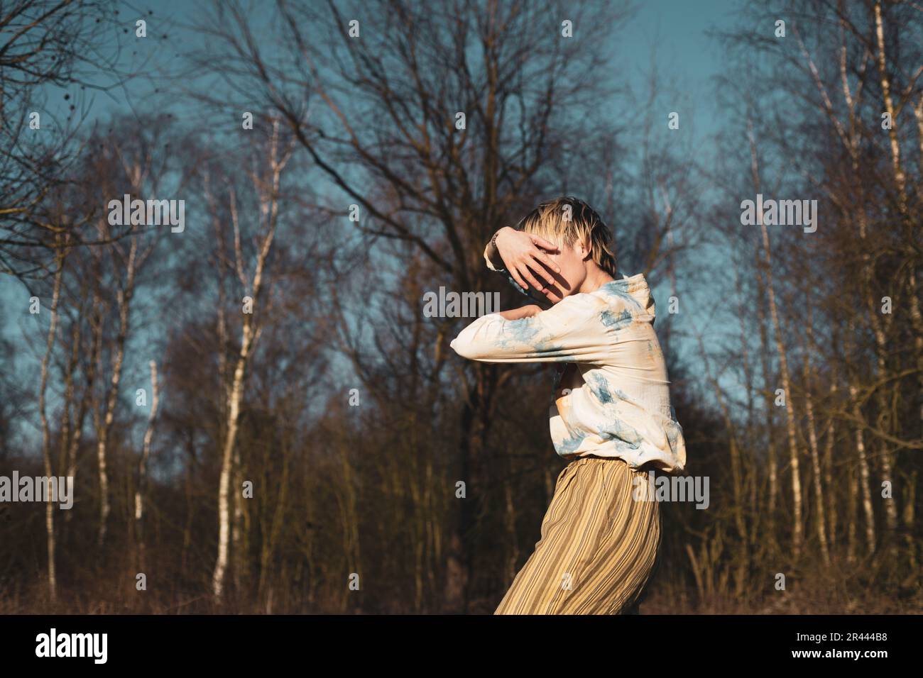immagine senza volto di danzatrice androgina al di fuori in sole d'inverno e alberi Foto Stock