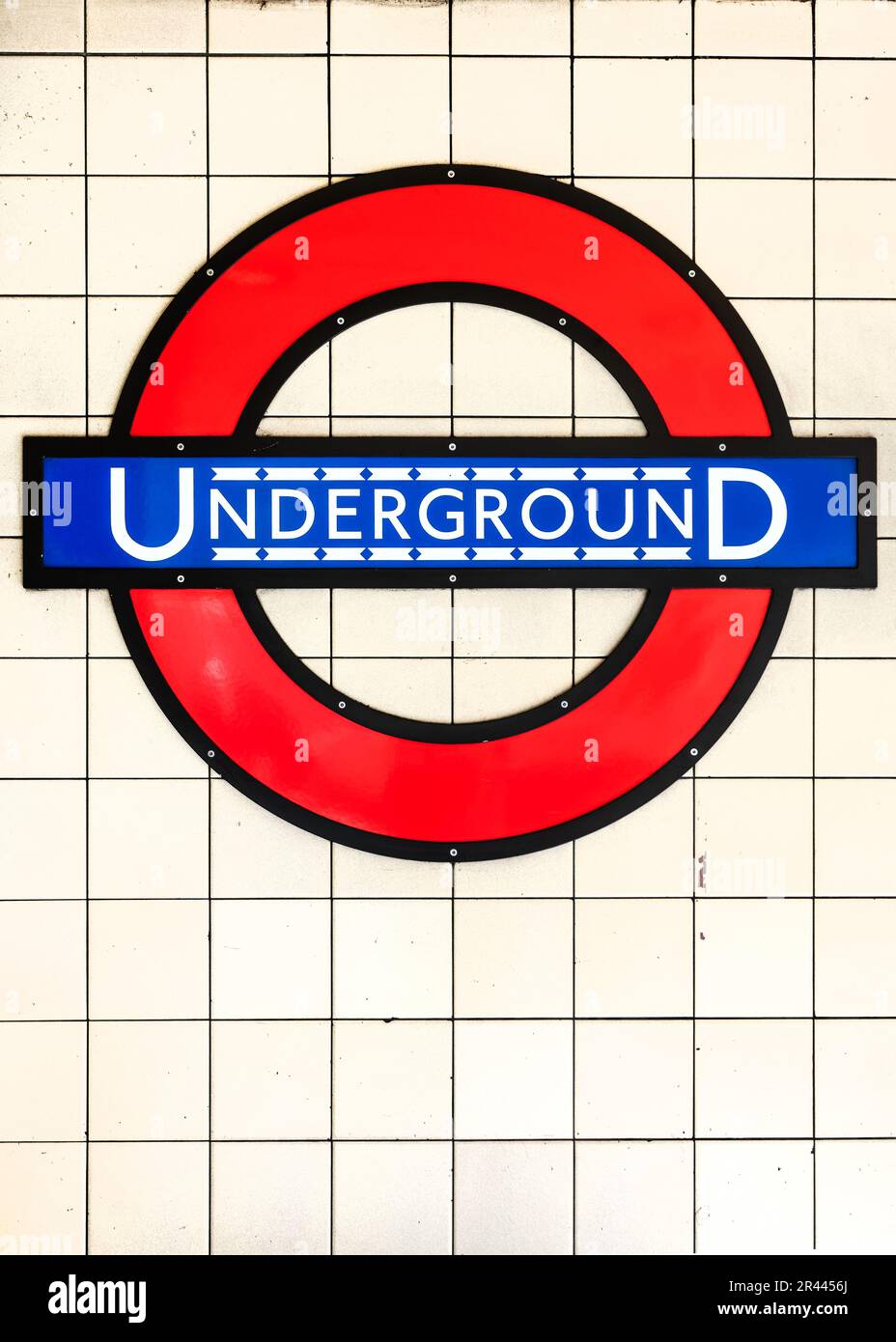 Segno blu e rosso della metropolitana su sfondo bianco piastrelle in una stazione della metropolitana a Londra, Regno Unito Foto Stock