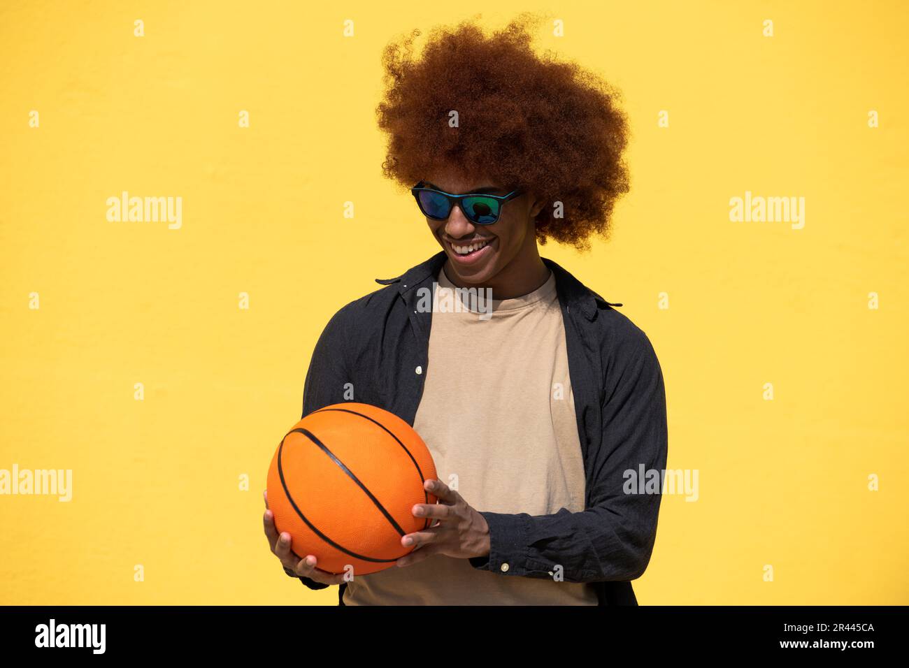 Isolato felice e gioioso riccio maschio con una palla basket Foto Stock