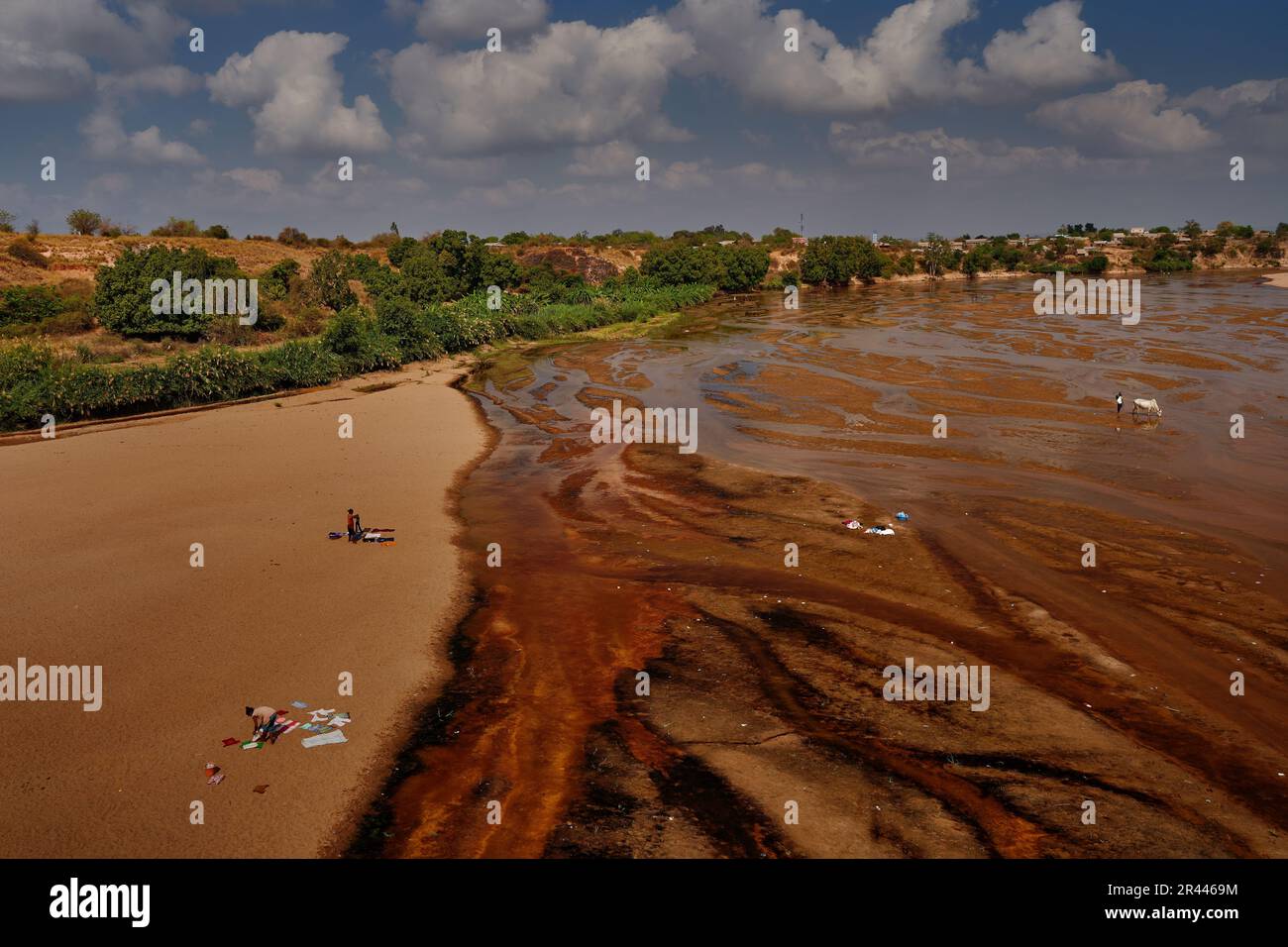 Paesaggio fluviale in Madagascar. lavare i vestiti nel grande fiume, giorno di sole con cielo blu e nuvola. Persone in Madagascar, donne in acqua. Foto Stock