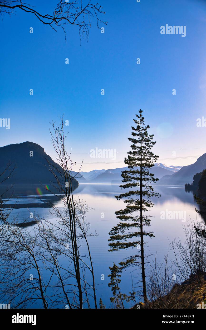 Vista del lago Oppstrynsvatnet in Norvegia nelle ore mattutine. Montagne innevate sullo sfondo. Acqua calma nel lago di montagna. Ripresa orizzontale avanti Foto Stock