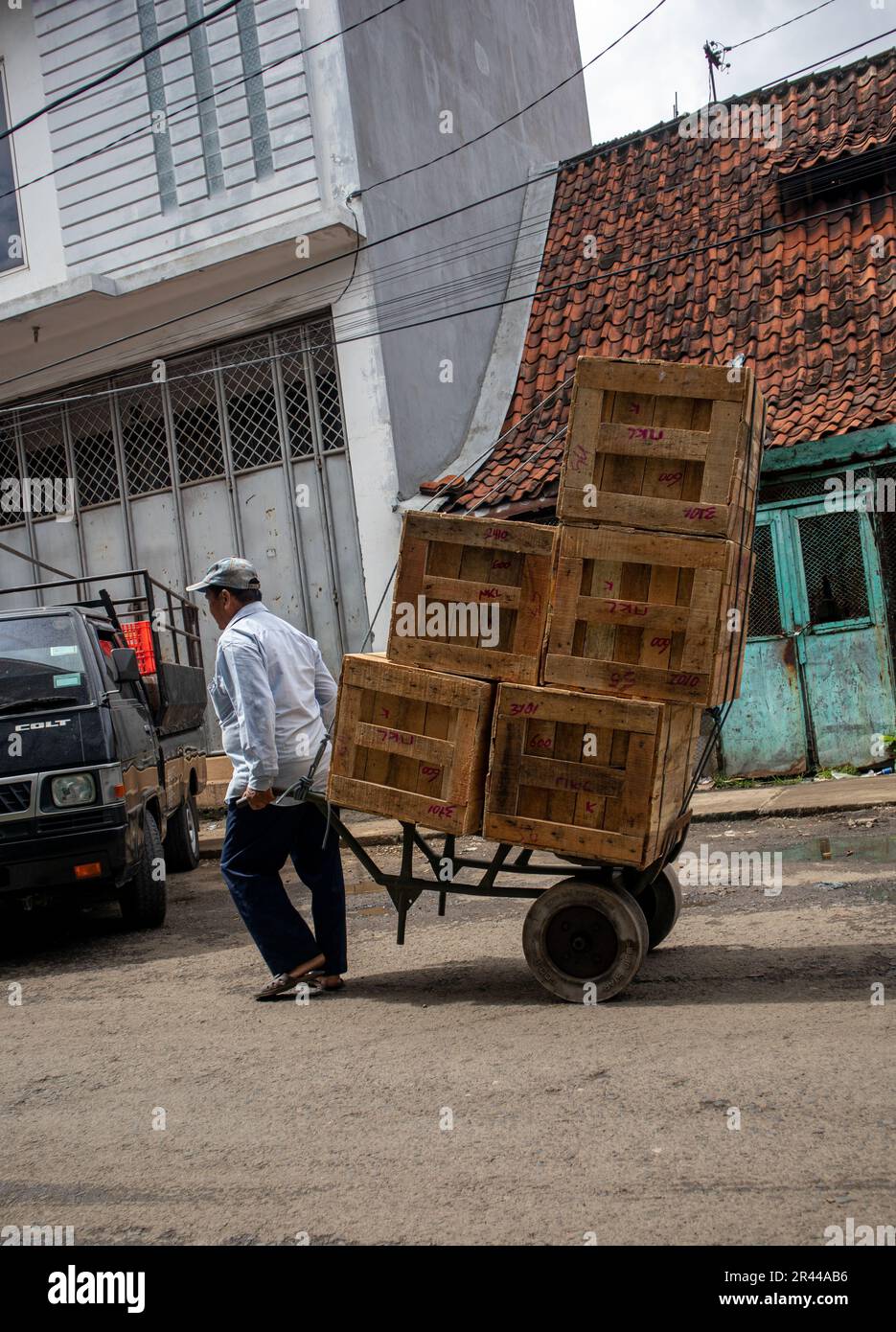 un uomo operaio trasporta merci con un carrello in un mercato tradizionale Foto Stock
